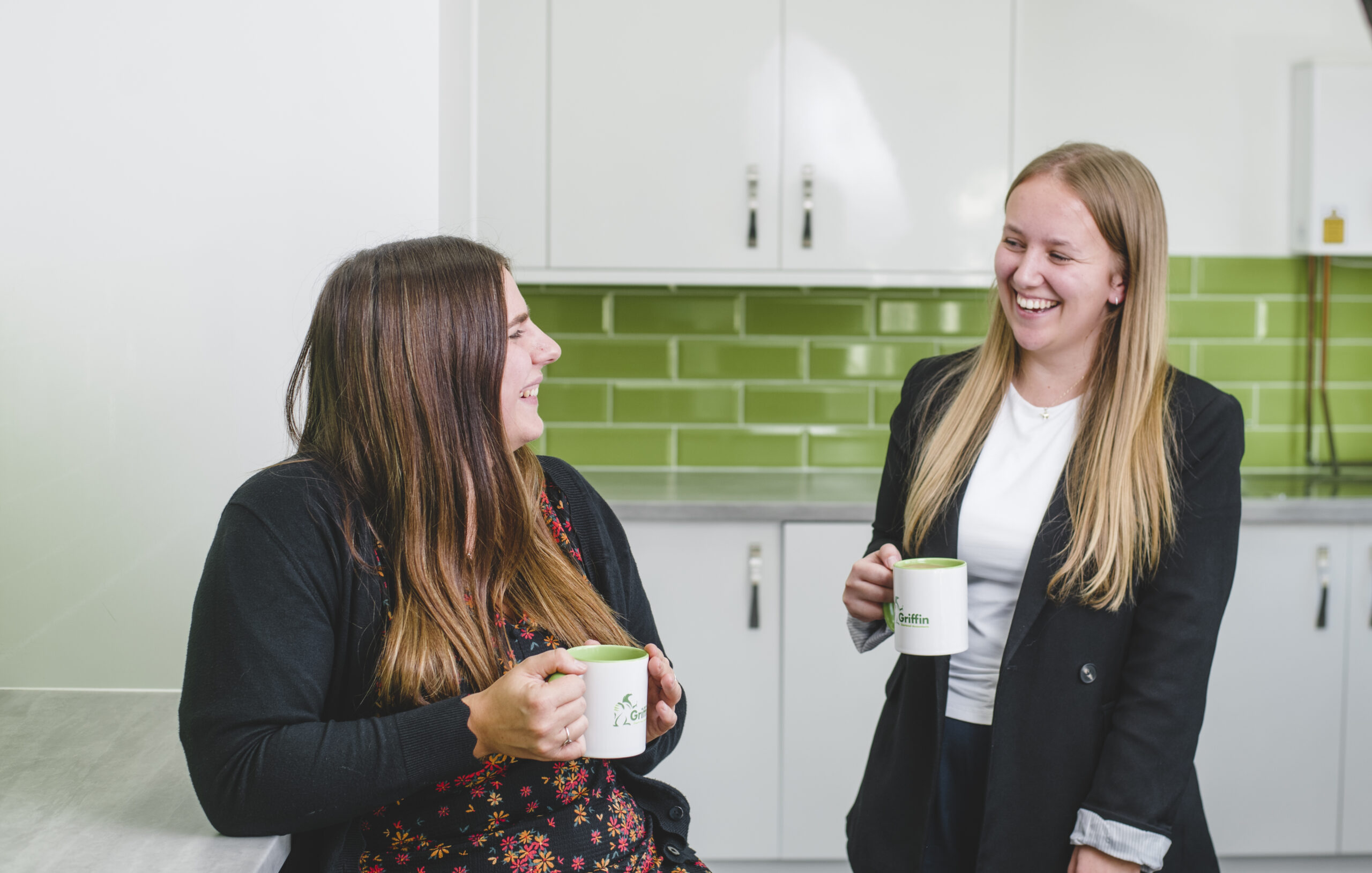 About Griffin Accountancy. Two members of the team chatting with coffee mugs in their hands